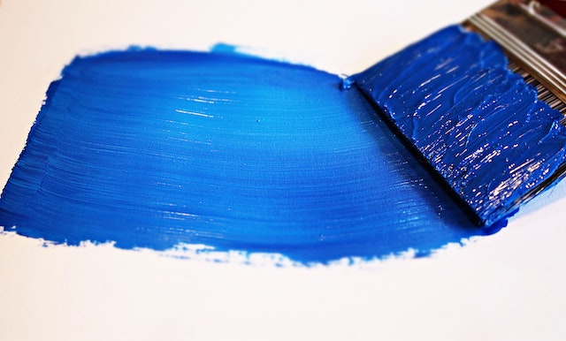 Blue paint smeared on a white canvas using a paint brush.