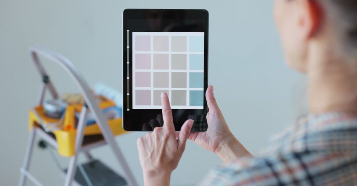 Person uses a tablet to select paint colors while planning an interior decorating project.