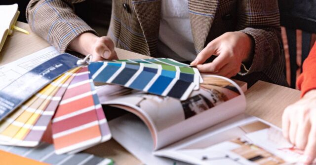 A woman choosing a color from various sample palettes.