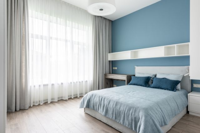 Bedroom with soft blue accent wall.
