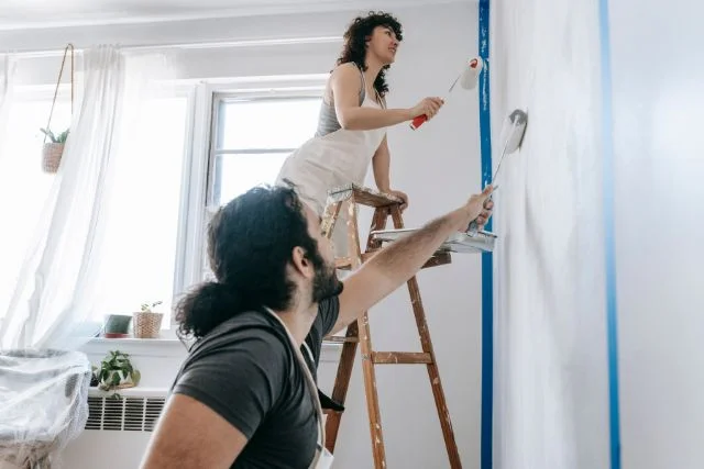 A happy couple painting a wall while having a perfect weather.