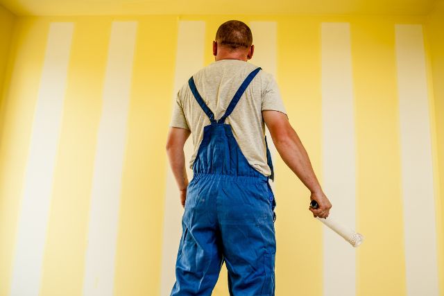 A professional painter looking at a freshly painted wall.
