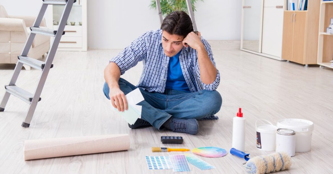 Man reviews paint samples and renovation supplies while planning improvements in an empty room.