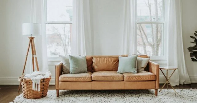 A living room with brown sofa chair and white walls and curtains.