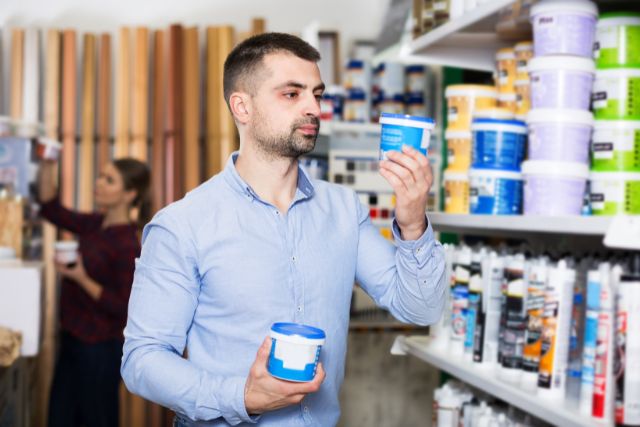 A man checking out different paint types in a store.