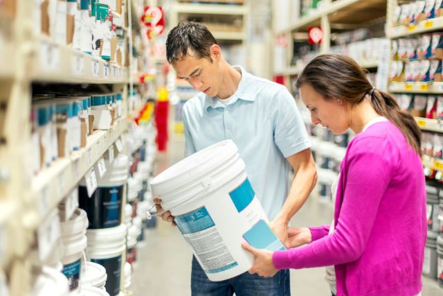 Couple shopping for paint and reading labels carefully.
