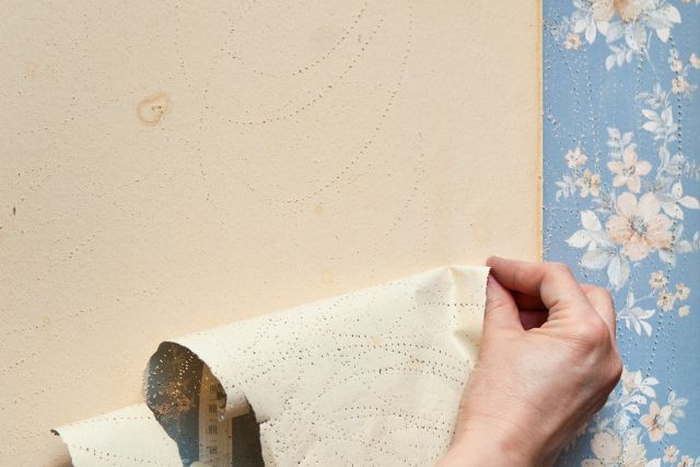 Peeling old wallpaper by hand.