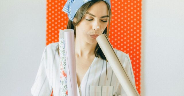 A woman is checking out different wallpapers to use in a house.