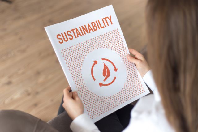 A woman holding a flyer about sustainability.
