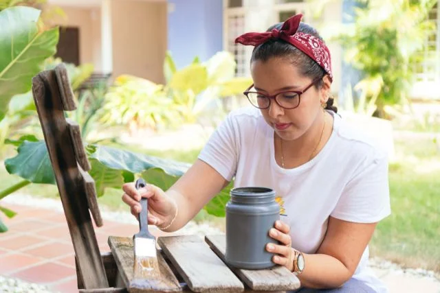 Woman with paint upcycling a chair at home.