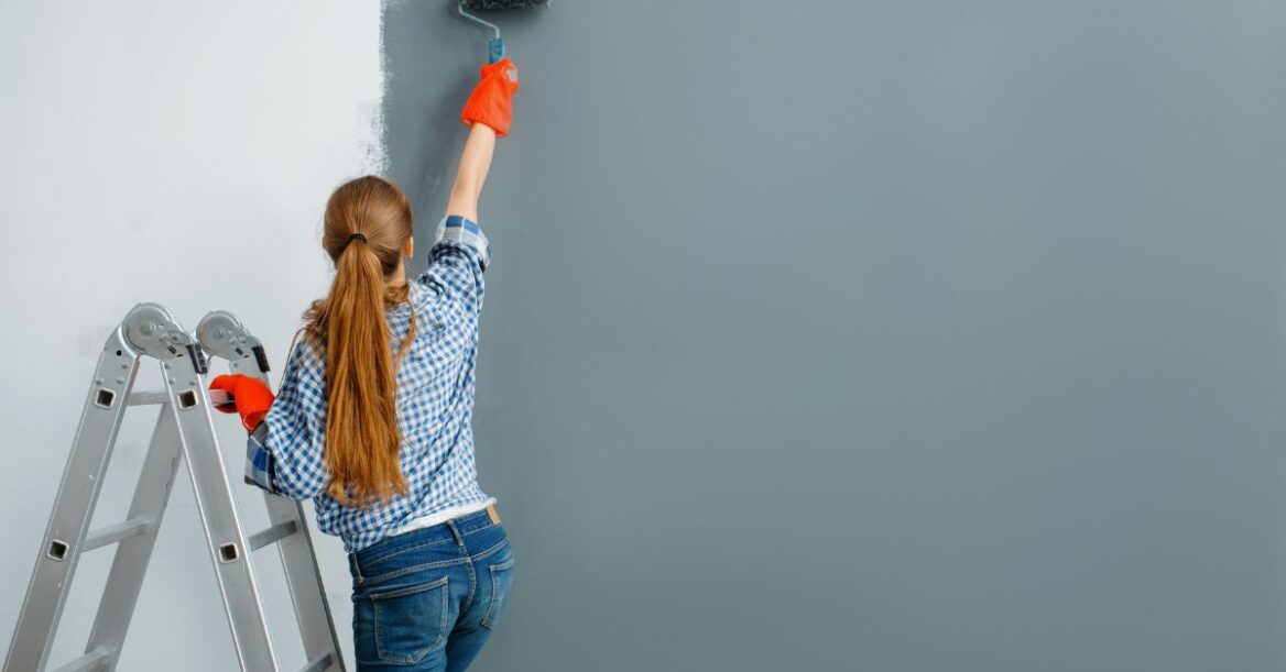 Female house painter working on wall with matte finish paint.