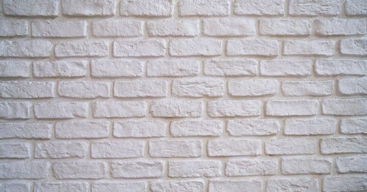 White painted brick wall with textured surface, ideal for modern interior or exterior design backgrounds.