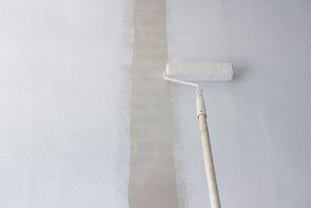 Paint primer applied using a long handled roller brush.