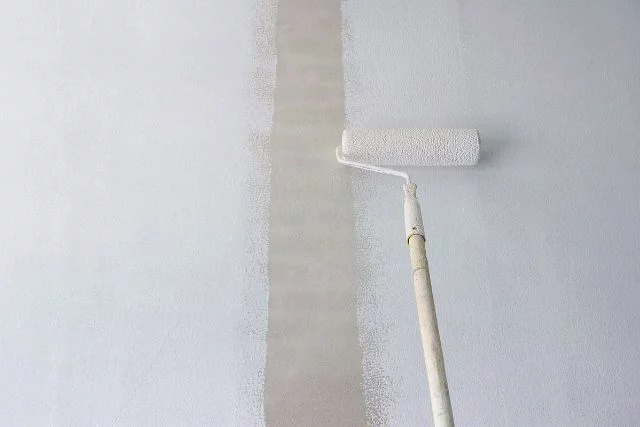 Paint primer applied using a long handled roller brush.