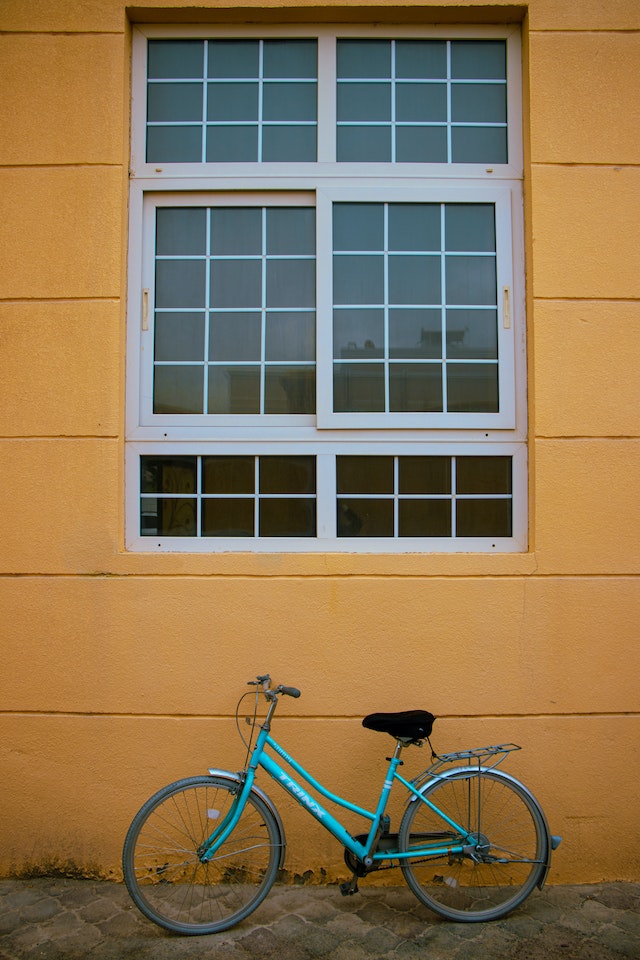 Yellow wall with a bicycle leaning on it.