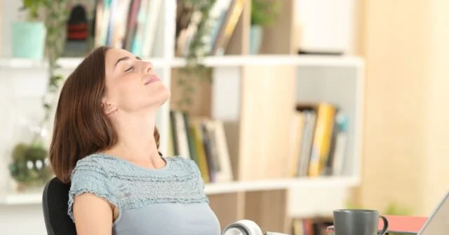 Women sitting on chair in home with head tilted back taking in a deep breath.