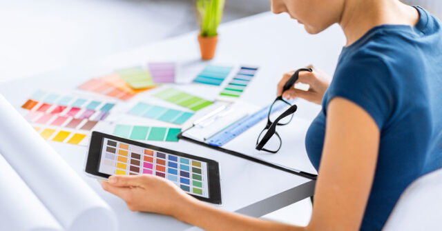 Women holding tablet with colour schemes and colour palettes in front of her.