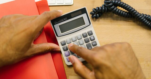 A man holding a calculator to determine the cost of house painting.