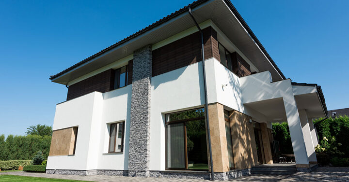 Exterior of a home with exposed stone and brick work painted in white, grey and brown to create an earthy colour scheme