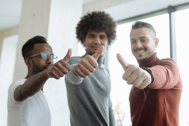 Three men holding a thumbs up and showing their approval.