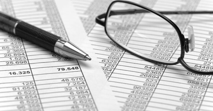 Two documents showing tracked spendings with a pen and glasses.