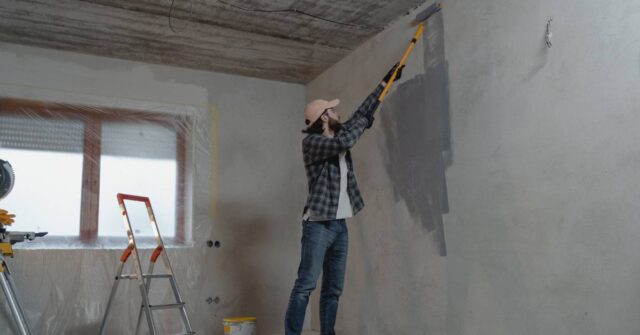 A man preparing the wall before painting it.