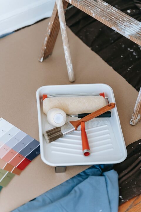 New paint roller and brush on a painting tray.