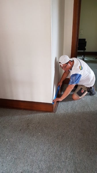 Lining skirting board with painting tape to ensure straight lines.