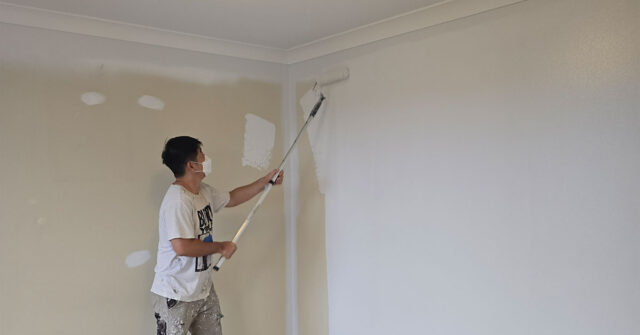 Interior painter using roller on walls and they have been patched and prepared.