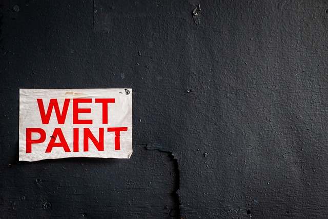 A wall with a wet paint sign attached to it.